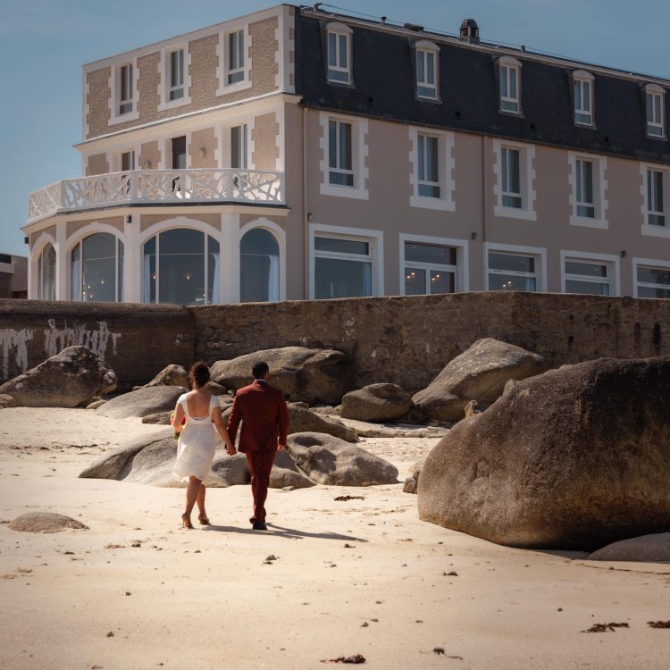 Couple de mariés marchant sur le sable — instant magique en bord de mer